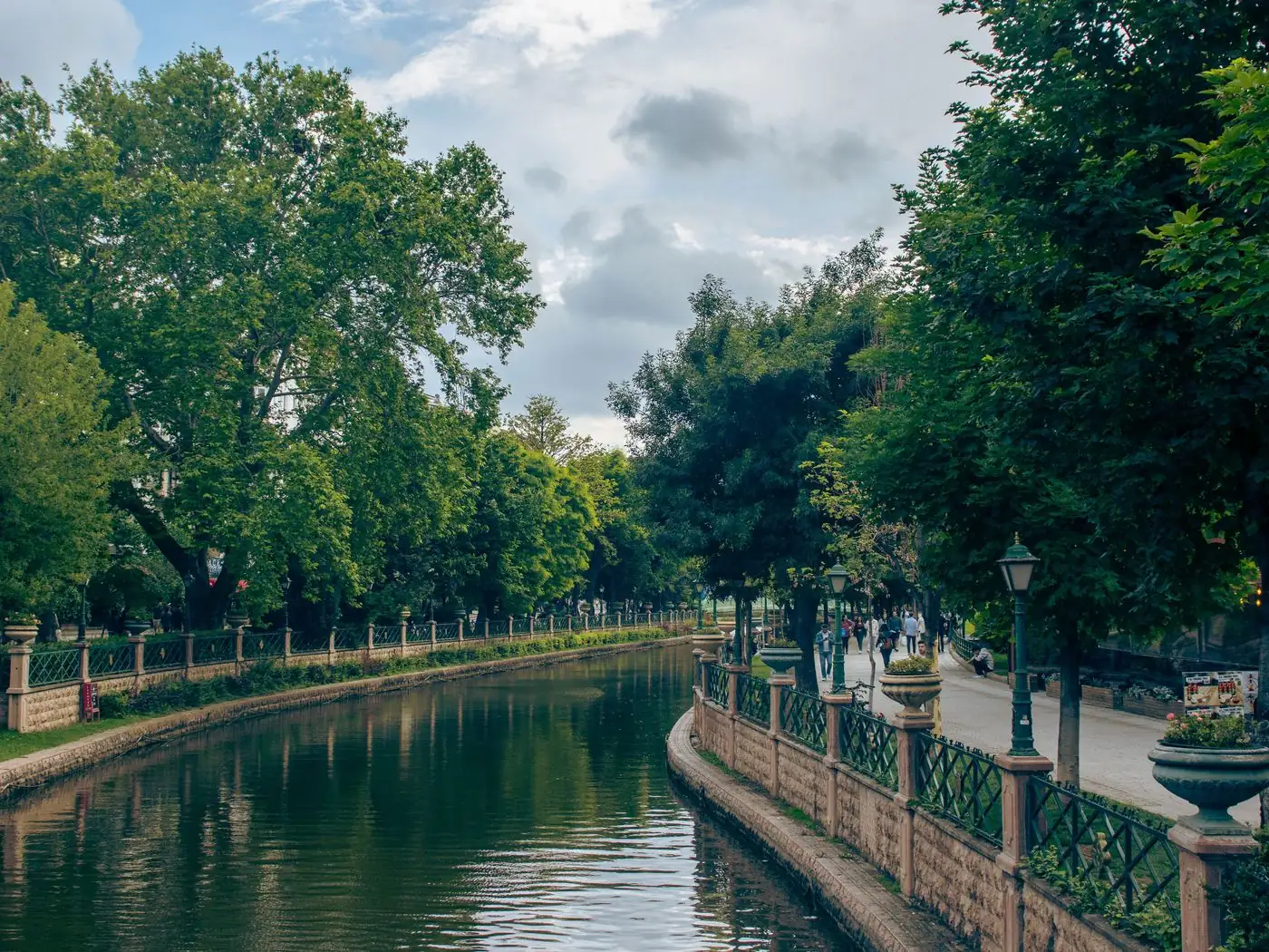 Een wandelpad met bomen, lantaarns en hekken langs de Porsuk